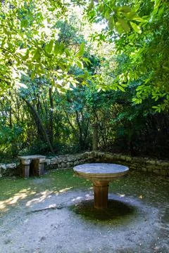 Round stone table between green nature in Trsteno Arboretum in Croatia. Stock Photos