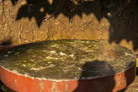 Round stone table with mossy surface against an earthy soil background Foto stock