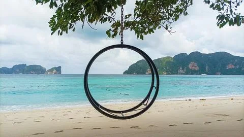 Round swing frame hanging under a tree on a serene tropical island beach Foto stock