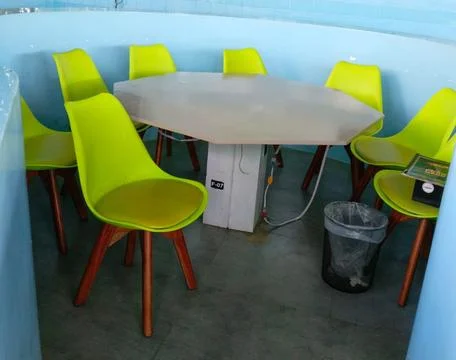 Round table with lime green chairs in a tiled room Stock Photos