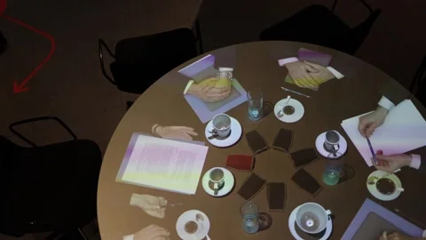 A round table set for an online conference displays holograms of participants’ h Stock Footage 290185111