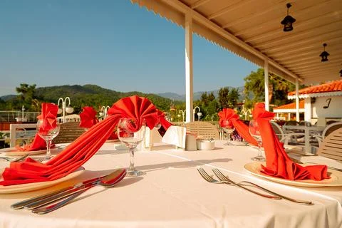 Round table is set with red napkins around  balcony. setting includes green t Stock Photos