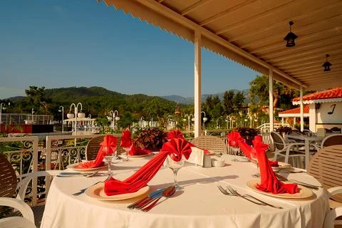 Round table is set with red napkins around  balcony. setting includes green t Stock Photos