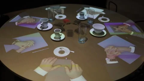 A round table setup for an online conference features holographic projections of Stock Footage 290184960