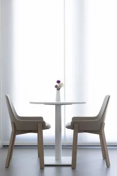 A round table with a vase and two wooden chairs Foto stock