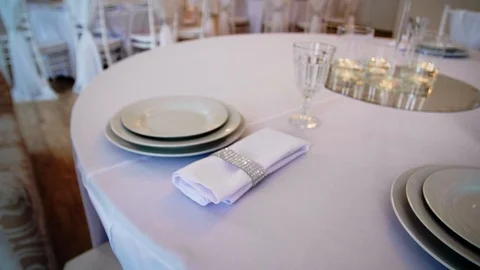 Round table with a white tablecloth served plates wine glasses and napkins Stock Footage 97718189