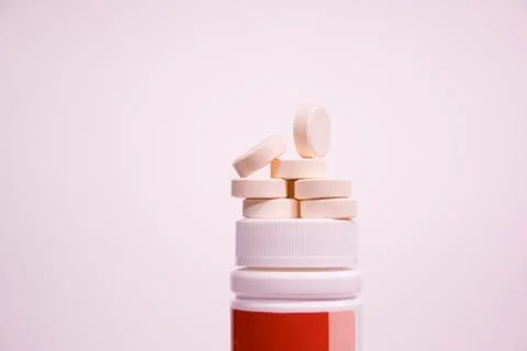 Round tablets are placed on a jar. Medicine and health. Stock Photos