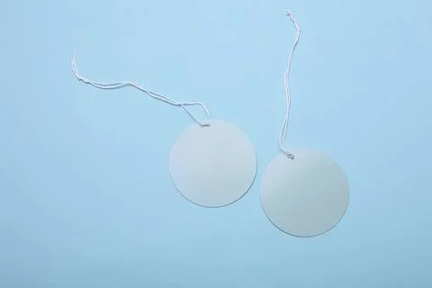 Round tags with strings on a light blue background Stock Photos