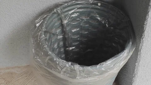 A round trash bin covered in plastic is placed in a corner. It sits on a light Stock Footage 342402839