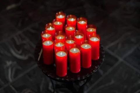 Round tray with multiple lit candles encapsulated in orange plastic Stock Photos