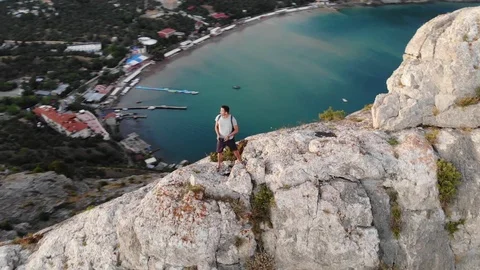 Round upper motion man stands on hill crest against sea Video stock 103180752