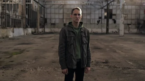 Round view of s serious guy standing in an abandoned factory building 動画素材 119549551