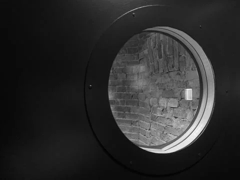 Round viewing window in the door. A window in a prison cell. Stock Photos