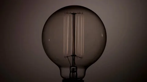 Round vintage light bulb vertical filaments glowing then fading Stock Footage 329657267