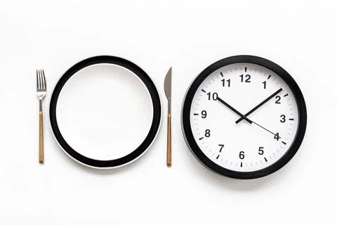 Round wall clock with empty dish. Diet concept. Time to eat 스톡 사진
