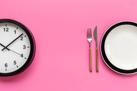 Round wall clock with empty dish. Diet concept. Time to eat 스톡 사진