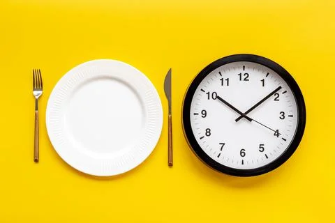 Round wall clock with empty plate. Diet or meal time concept Foto stock