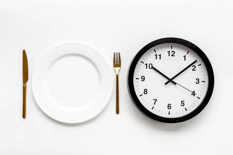 Round wall clock with empty plate. Diet or meal time concept Foto stock