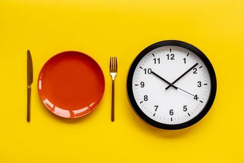 Round wall clock with empty plate. Diet or meal time concept Foto stock