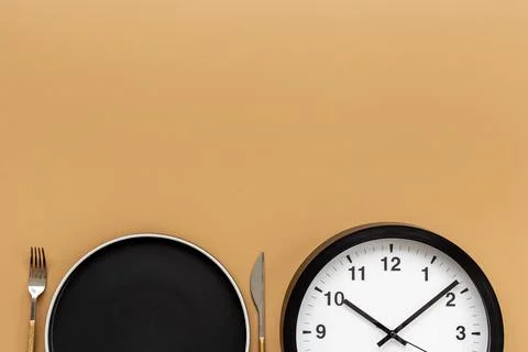 Round wall clock with empty plate. Diet or meal time concept 스톡 사진