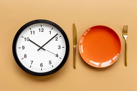 Round wall clock with empty plate. Diet or meal time concept 스톡 사진