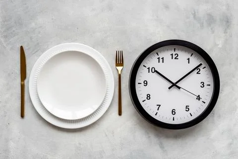 Round wall clock with empty plate. Diet or meal time concept 스톡 사진