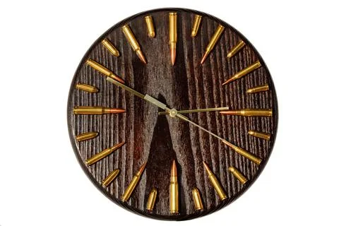 Round wall clock made of solid wood with cartridges and bullets in a circle i Stock Photos