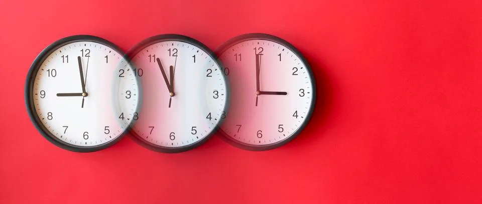 Round wall clocks on red surface showing 9, 12, 3, layout, top view Stock-Fotos
