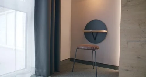Round Wall Mirror With Lamp Glows Over Designer Chair In Hotel Room Vídeo Stock 340265174