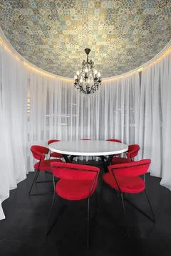 Round white dining table with red chairs Stock Photos