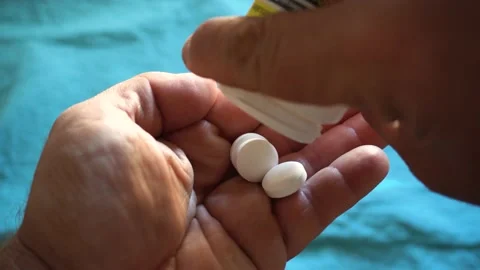Round white pills falling from a pot onto a hand. Stock Footage 162817701