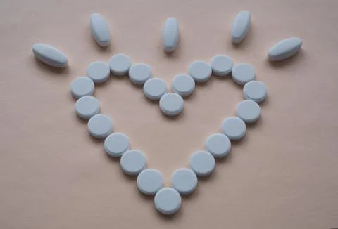 Round white pills in the shape of an empty heart Stock Photos