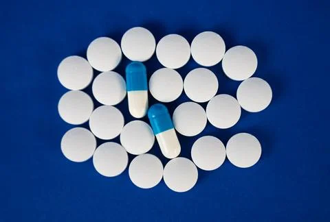 Round white tablets arranged in circle on blue background Stock Photos