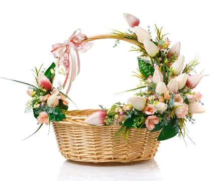 Round wicker basket with Easter flower arrangements on the handle of the bask Photos