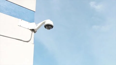 Round wide angle security camera mounted on corner of building wall in summer Stock Footage 250275626