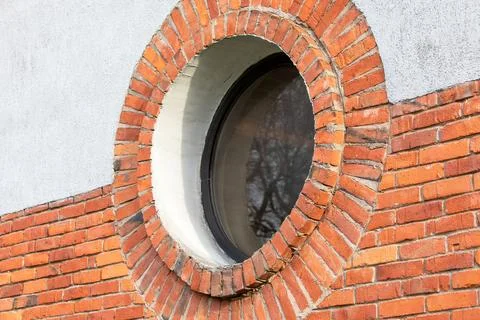 Round window. Red brick wall and light plaster Stock Photos