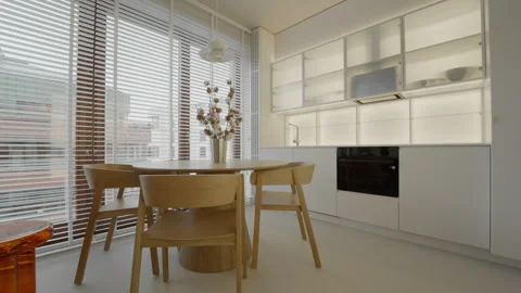Round wooden dining table with chairs in white kitchen apartment interior. Stock Footage 335540784