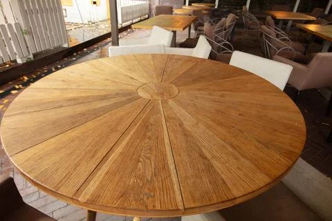 Round wooden table set for dining with empty chairs in outdoor restaurant a.. Stock Photos