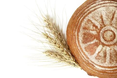 Round yeast-free rye bread and ears of rye on a white isolated background. To Stock Photos