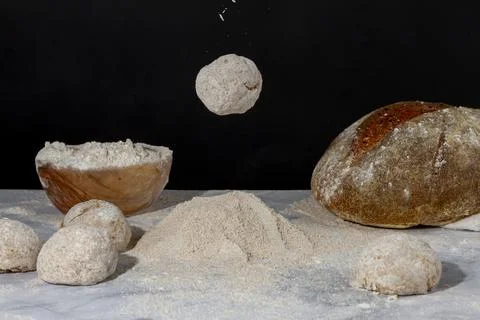 A rounded bread dough is falling on to a pile of flour on marble countertop. Stock Photos