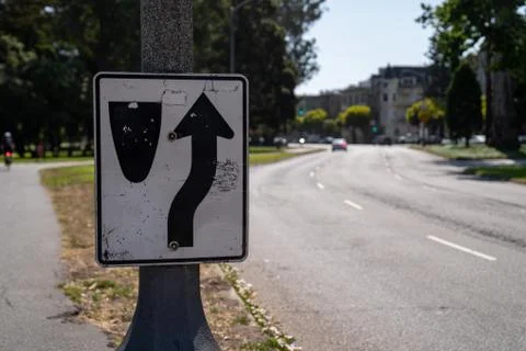 Rounded curve corner warning sign on light post at city street Foto stock