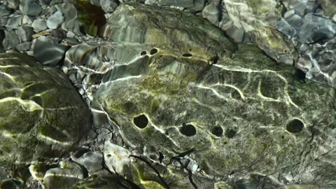 Roundish moving shadows on the ground of a mountain stream (slow motion) Video stock 260842981