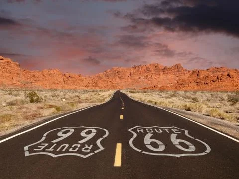 Route 66 pavement sign with red rock mountain sunset Stock Photos
