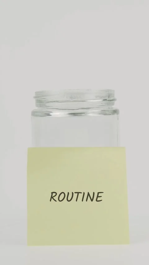 Routine text or word on yellow sticky note attached to glass jar with hand Stock Footage 311782835