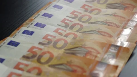 Row of 50 Euro notes laid flat on a dark table surface with slow zoom out Video stock 183478739
