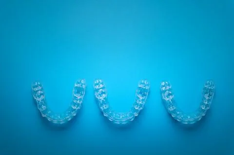 Row of aligners, side view, on a blue background Stock Photos