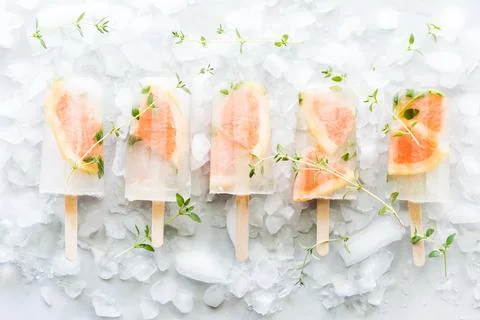 A row of beautiful grapefruit thyme popsicles on a bed of ice. Stock Photos