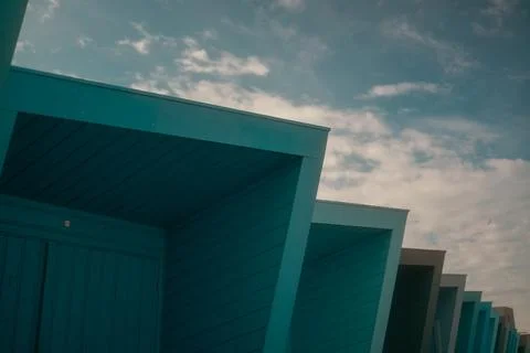 Row of Blue Beach Huts Under Cloudy Sky Foto stock