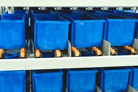 A row of blue plastic containers with orange handles are stacked on top of ea Foto stock
