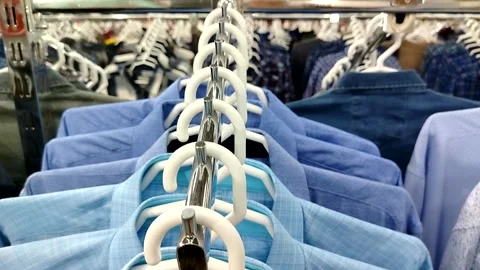 Row of blue shirts on hangers close up rail perspective camera movement product  Stock Footage 320407644